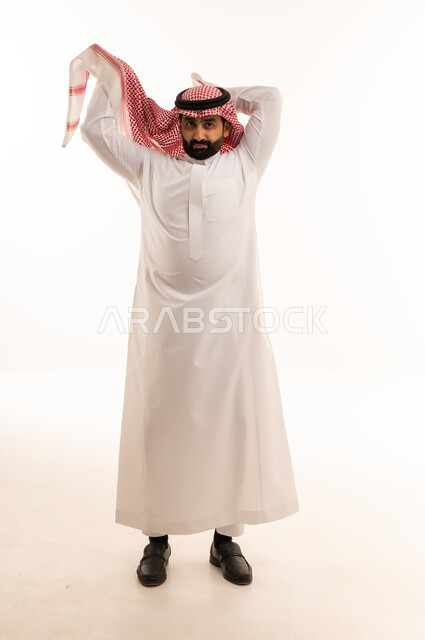 رجل سعودي بالزي التقليدي يعدل الشماغ