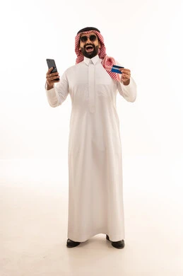 رجل سعودي يحمل بطاقة ائتمان وهاتف ذكي للتسوق الإلكتروني