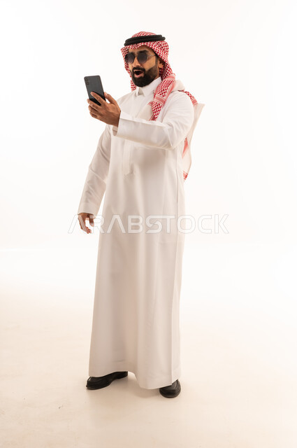 رجل سعودي مع هاتف ذكي بتعابير وجه مندهشة