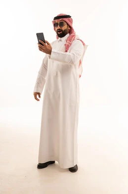 رجل سعودي مع هاتف ذكي بتعابير وجه مندهشة