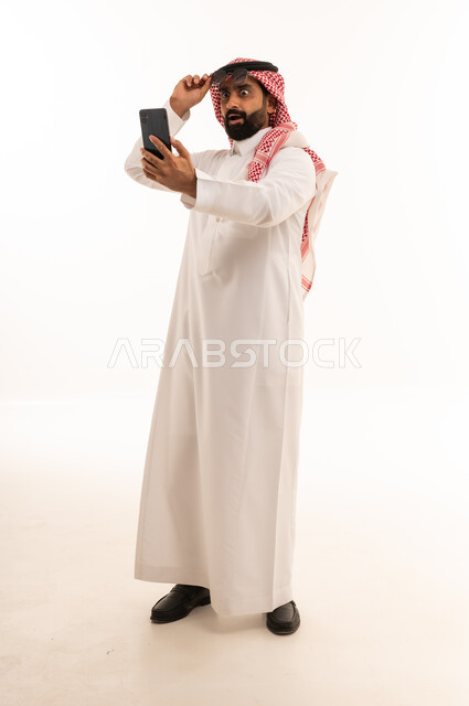 رجل سعودي مصدوم ينظر إلى هاتف ذكي في استوديو