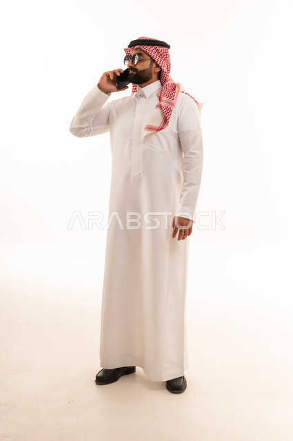 Saudi Man in Traditional Thobe Talking on Smartphone
