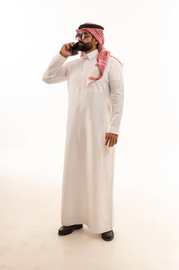 Saudi Man in Traditional Thobe Talking on Smartphone