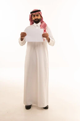 رجل سعودي يحمل ورقة بيضاء فارغة في الاستوديو