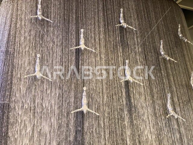صورة لتماثيل مجموعة من الغطاسين معلقة وسط شلال ، شلال دبي مول ، غواصي اللؤلؤ ، اماكن سياحية في الامارات العربية المتحدة 