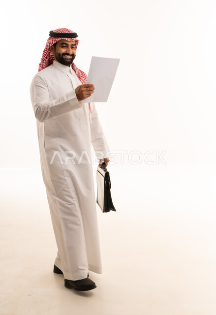 رجل أعمال سعودي بالزي التقليدي يحمل وثيقة وحقيبة
