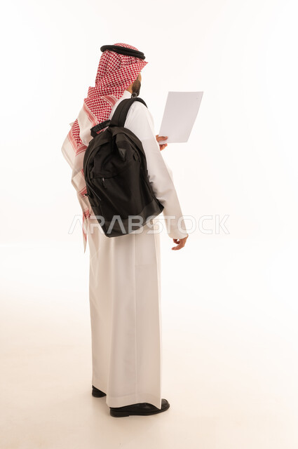 رجل سعودي بالزي التقليدي يحمل حقيبة ظهر وورقة بيضاء