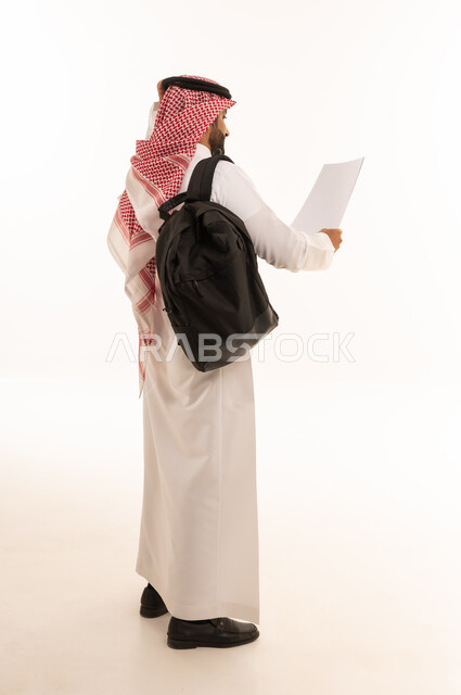 Saudi Man in Thobe with Backpack Reading Paper