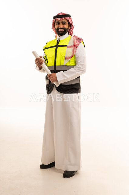 مهندس سعودي يرتدي سترة السلامة ويحمل مخططات