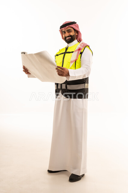 مهندس سعودي يحمل مخططات هندسية بزي السلامة