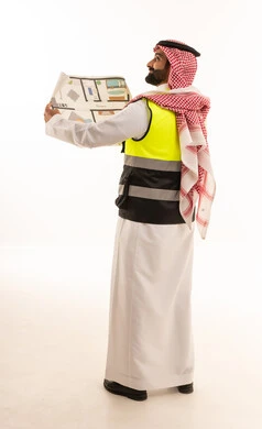 مهندس سعودي يرتدي سترة السلامة ويمسك مخطط بناء