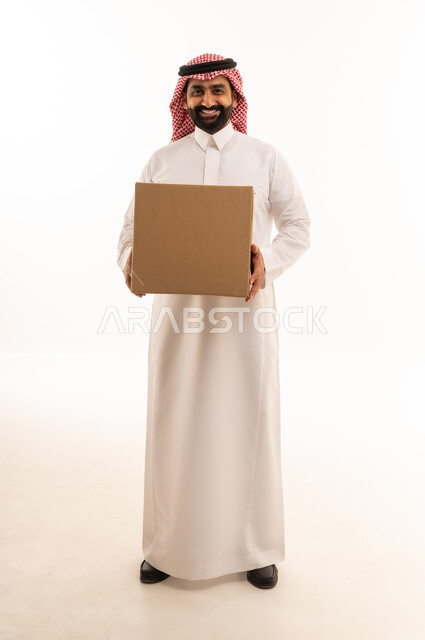 رجل سعودي يحمل صندوق شحن كرتوني بخلفية بيضاء