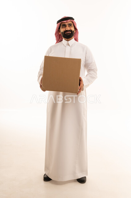 رجل سعودي بالثوب يحمل صندوق طرد كرتوني