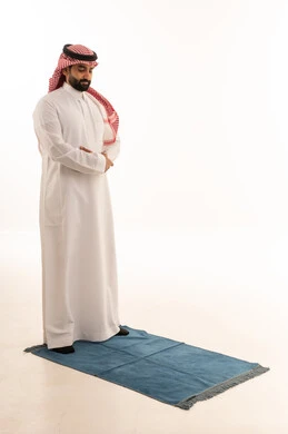 رجل سعودي يصلي على سجادة صلاة زرقاء
