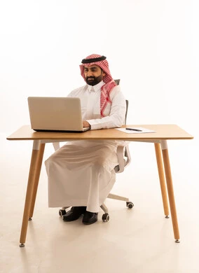 Saudi Businessman Working on Laptop at Wooden Office Desk