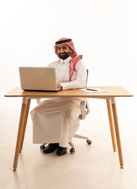 رجل أعمال سعودي مع كمبيوتر محمول على المكتب