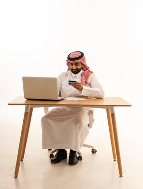 Saudi Man Using Laptop and Credit Card for Online Shopping