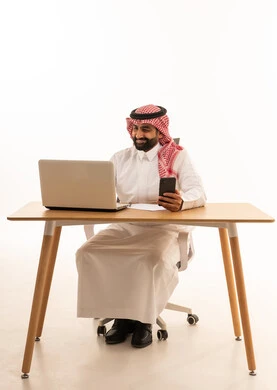 Saudi Businessman at Desk with Laptop and Phone