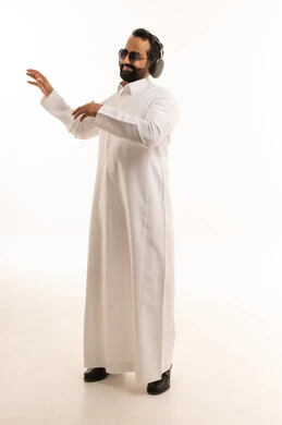 Saudi Man in Thobe Listening to Music with Headphones