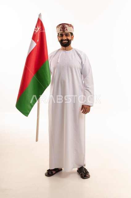 رجل عماني بالزي التقليدي يحمل علم سلطنة عمان