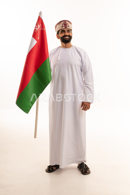 رجل عماني يحمل العلم الوطني بالزي التقليدي