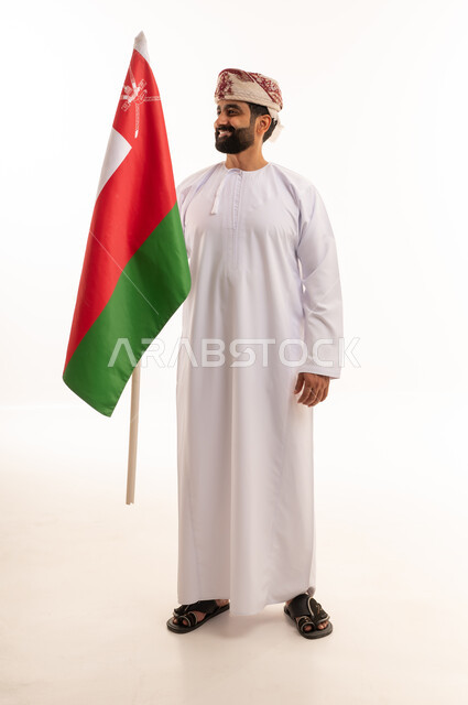 رجل عماني بالزي التقليدي يحمل علم سلطنة عمان