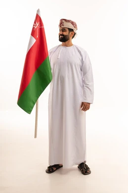 رجل عماني بالزي التقليدي يحمل علم سلطنة عمان