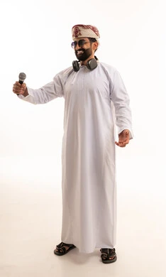 رجل عماني يرتدي الزي التقليدي يمسك ميكروفون