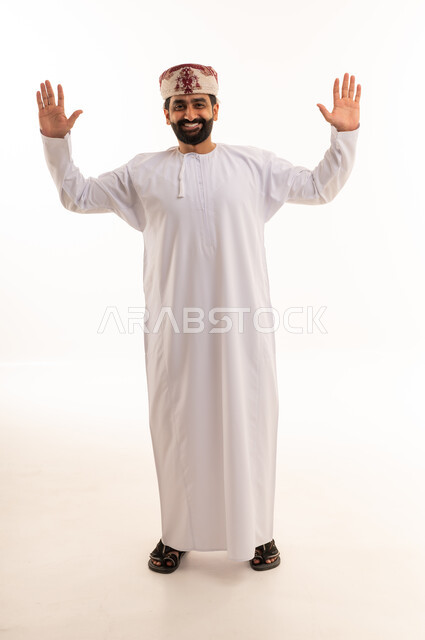 رجل عماني بالزي التقليدي يرفع يديه على خلفية بيضاء