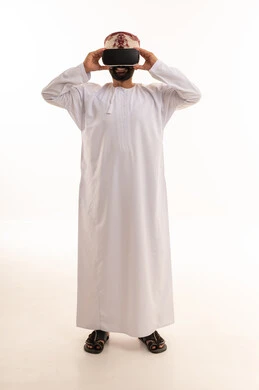 رجل عُماني يرتدي نظارة واقع افتراضي بخلفية بيضاء