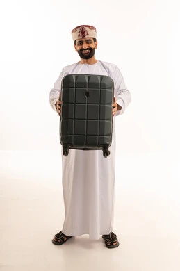 رجل عماني مع حقيبة سفر على خلفية بيضاء