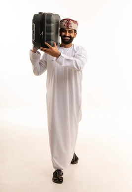 رجل عماني يحمل حقيبة سفر على خلفية بيضاء