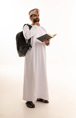 طالب عماني بالزي التقليدي يفكر حاملاً كتاباً