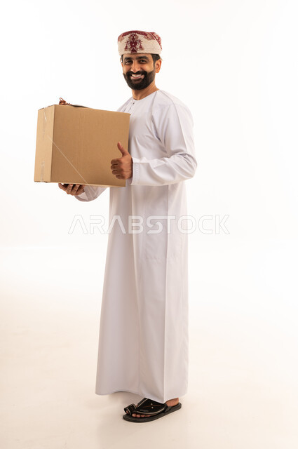 رجل عماني يحمل صندوق شحن مع إيماءة الإبهام