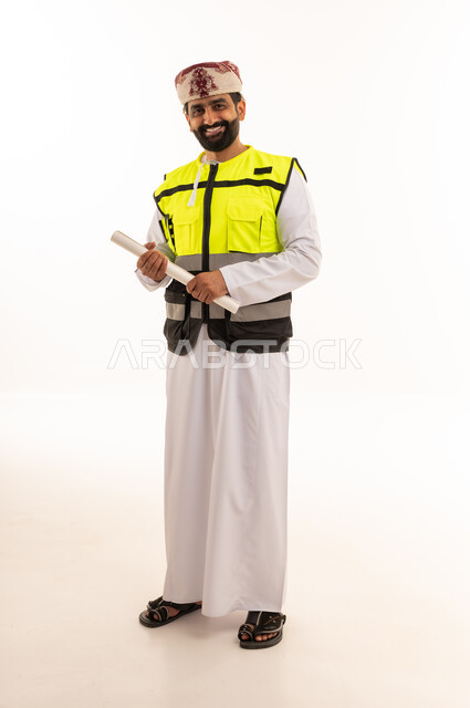 مهندس عماني بزي السلامة يمسك مخططات معمارية
