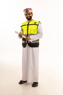 مهندس عماني بزي السلامة يمسك مخططات معمارية