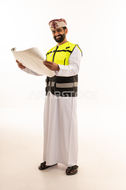 مهندس عماني يحمل مخططاً هندسياً مع سترة السلامة