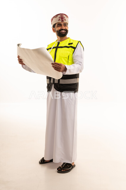 مهندس عماني يمسك مخططات هندسية بزي السلامة