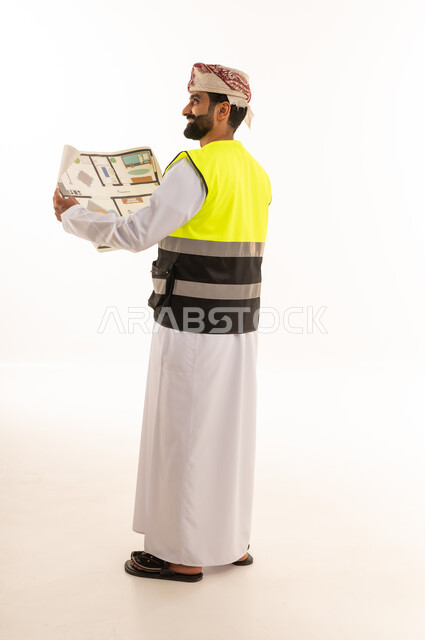 مهندس عماني يمسك بمخطط بناء بالزي الرسمي