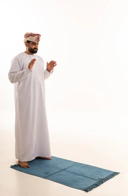 Omani Man in Traditional Dress Praying on Blue Mat