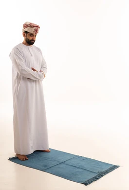 رجل عماني يؤدي الصلاة بالزي التقليدي