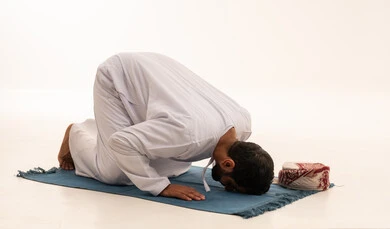 رجل عماني في وضعية السجود بالدشداشة التقليدية