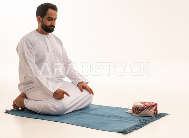 رجل إماراتي يصلي بالكندورة البيضاء التقليدية