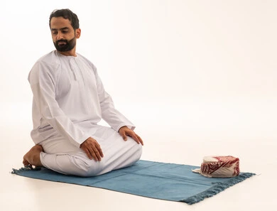 Emirati Man Performing Tashahhud Prayer on Blue Mat