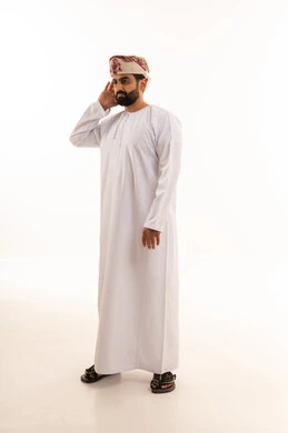 رجل عماني بالزي التقليدي يضع يده على أذنه