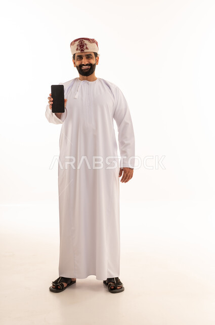 رجل عماني بالزي التقليدي يحمل هاتف ذكي