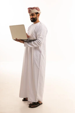 رجل عُماني يستخدم الكمبيوتر المحمول بالزي التقليدي