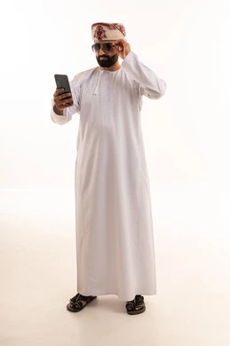 رجل عماني بالزي التقليدي يستخدم الهاتف الذكي