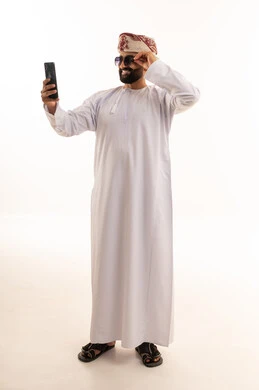 رجل عماني بالزي التقليدي يستخدم الهاتف الذكي سيلفي