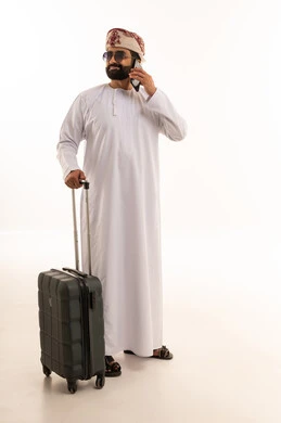 Omani Man with Suitcase Talking on Mobile Phone